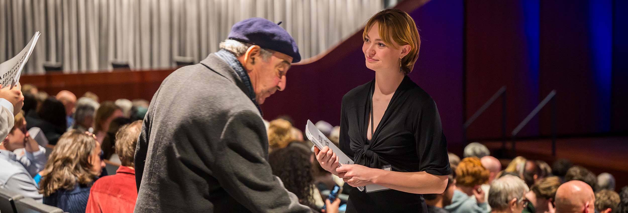 An usher directs a patron to their seat.